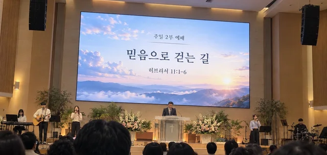 교회 본당 강단 뒤 LED 화면에 주일 예배 설교 제목이 표시된 예배 장면