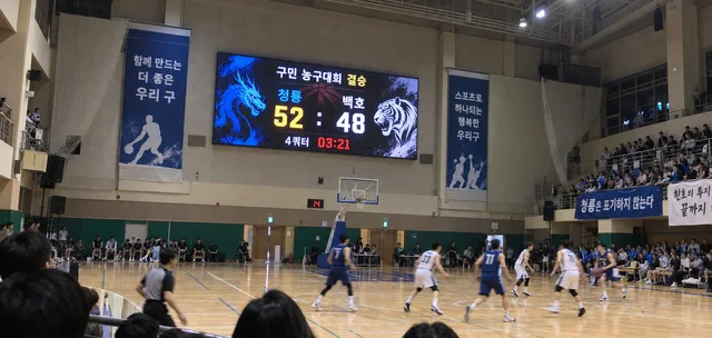 체육관 벽면 LED 화면에 농구대회 점수와 경기 시간이 표시된 경기 장면