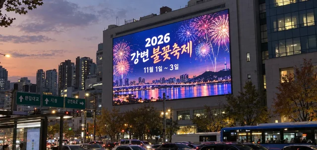 도로변 건물 벽면 대형 옥외 LED 전광판에 지역 축제 광고가 표시된 해 질 녘 모습