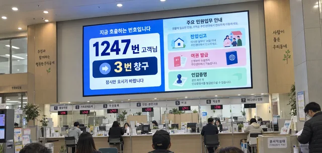 주민센터 민원실 창구 위 LED 화면에 번호 호출과 민원 업무 안내가 표시된 모습
