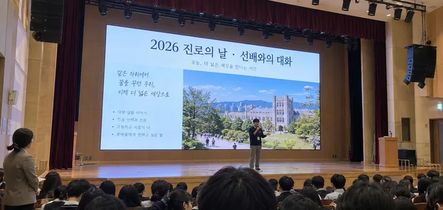 학교 강당 무대 LED 화면에 진로의 날 행사 발표 자료가 표시된 모습